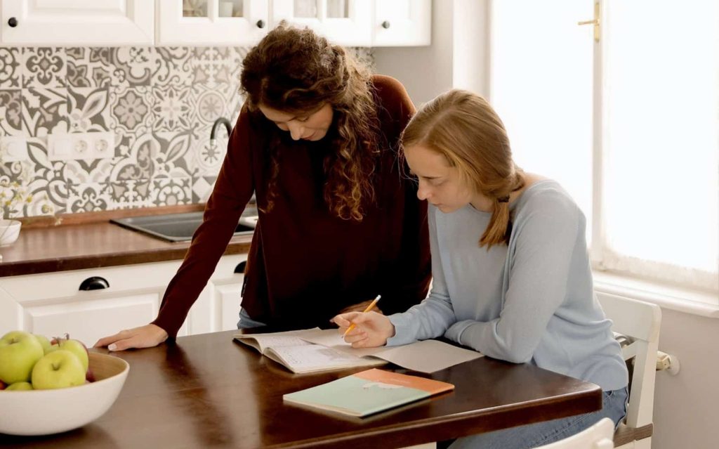 Two young women collaborating on a project in the kitchen.