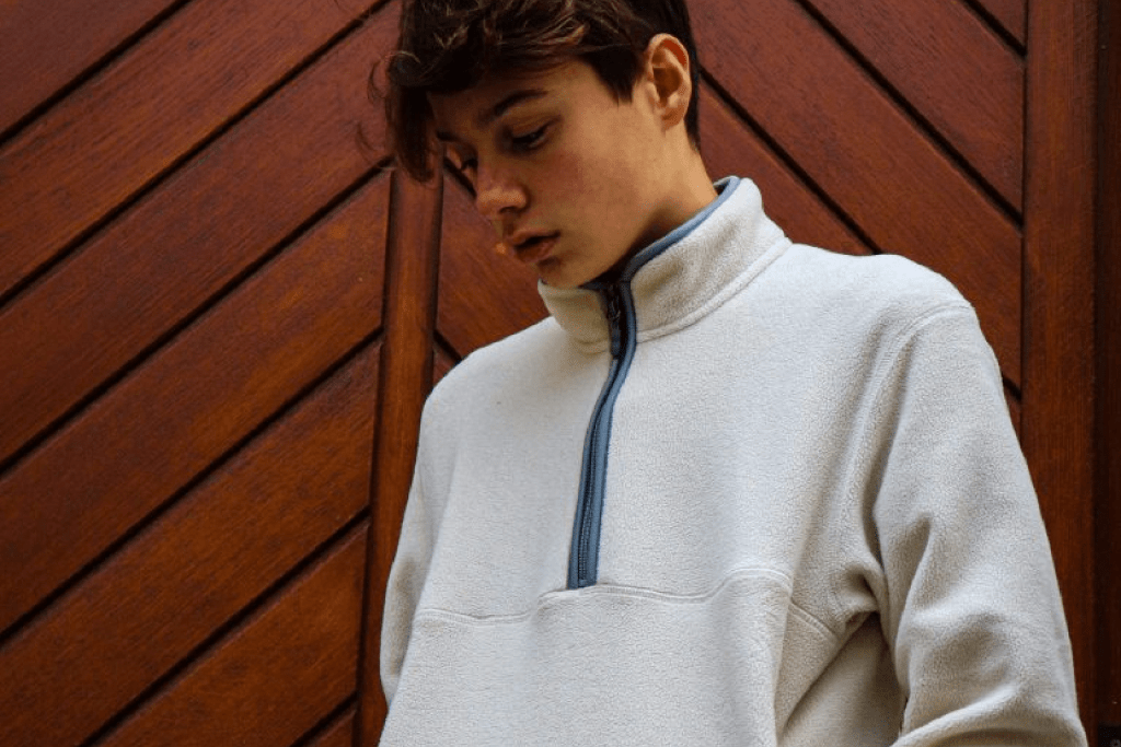 A young man in a white sweater standing outdoors.