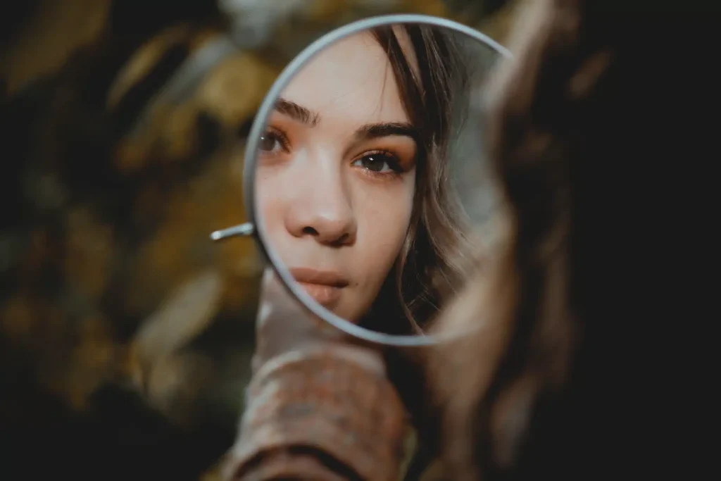 A woman gazing at her reflection in a mirror.