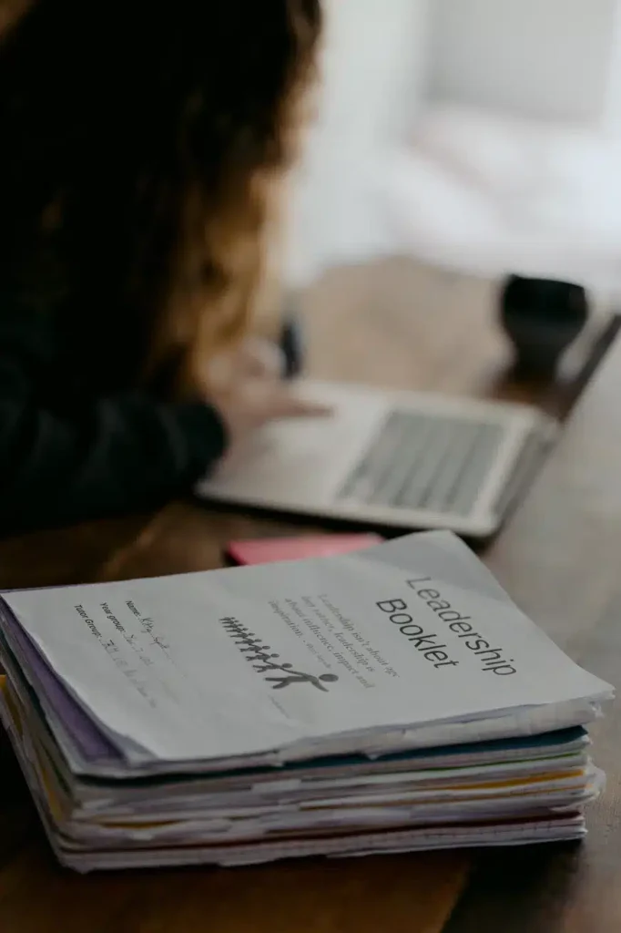 A woman working at a desk with a laptop and a leadership book. She's focused and ready to conquer the world!